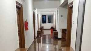Un largo pasillo pulido con bancos de madera y un extintor en la pared.