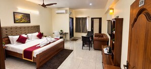 A hotel room with a bed, a desk, a chair, a wardrobe, and a ceiling fan. - Hotel Kvr Residency Tada  (Tada)