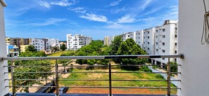 A balcony with a metal railing overlooking a residential area with multi-story buildings and greenery. - Hotel Kvr Residency Tada  (Tada)