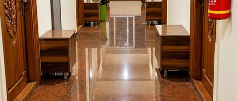 A hallway with polished tile flooring, wooden doors, and a fire extinguisher mounted on the wall.