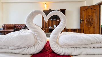 Una camera d'albergo con un letto, una coperta rossa, un divano in pelle marrone, un armadietto in legno e una porta in legno con motivo floreale.