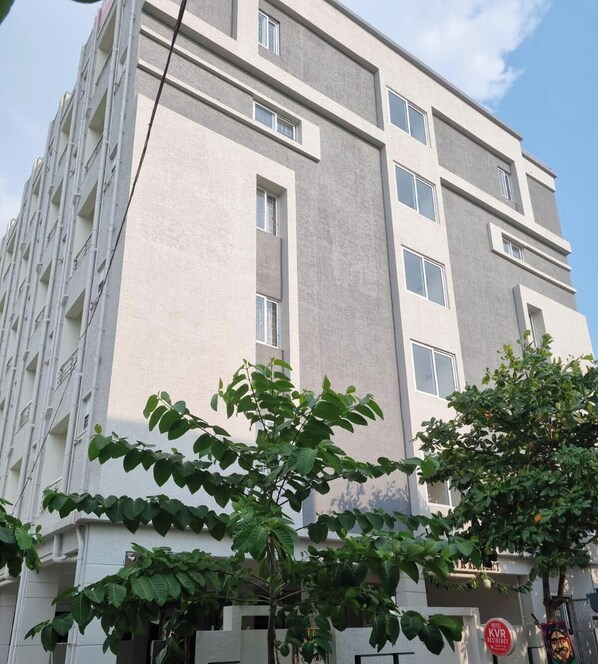 A multi-story building with a modern architectural style, featuring a flat facade, large windows, and a visible entrance with signage.