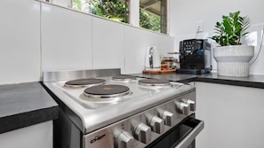 A modern kitchen with a stainless steel stove, white cabinets, and a coffee maker on the counter.