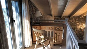 A wooden interior with a stone wall, a chair, a table, and a lamp.