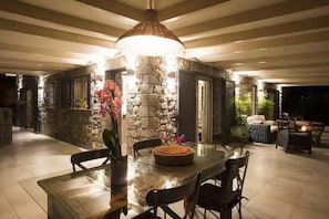An outdoor dining area with a stone wall, a large pendant light, and a table with chairs. - House Sleeps 6 With Pool and Parking (Ayia Napa)