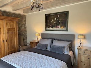 A bedroom with a large bed, a wooden wardrobe, a painting, and a chandelier. - House Sleeps 6 With Pool and Parking (Ayia Napa)