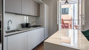 A modern kitchen with a marble countertop, stainless steel sink, and a built-in stove.