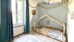 A child's bedroom with a wooden bunk bed, a window with curtains, a radiator, and a wall-mounted air conditioner. - Large family home in the heart of the village (Sainte-Cécile-les-Vignes)