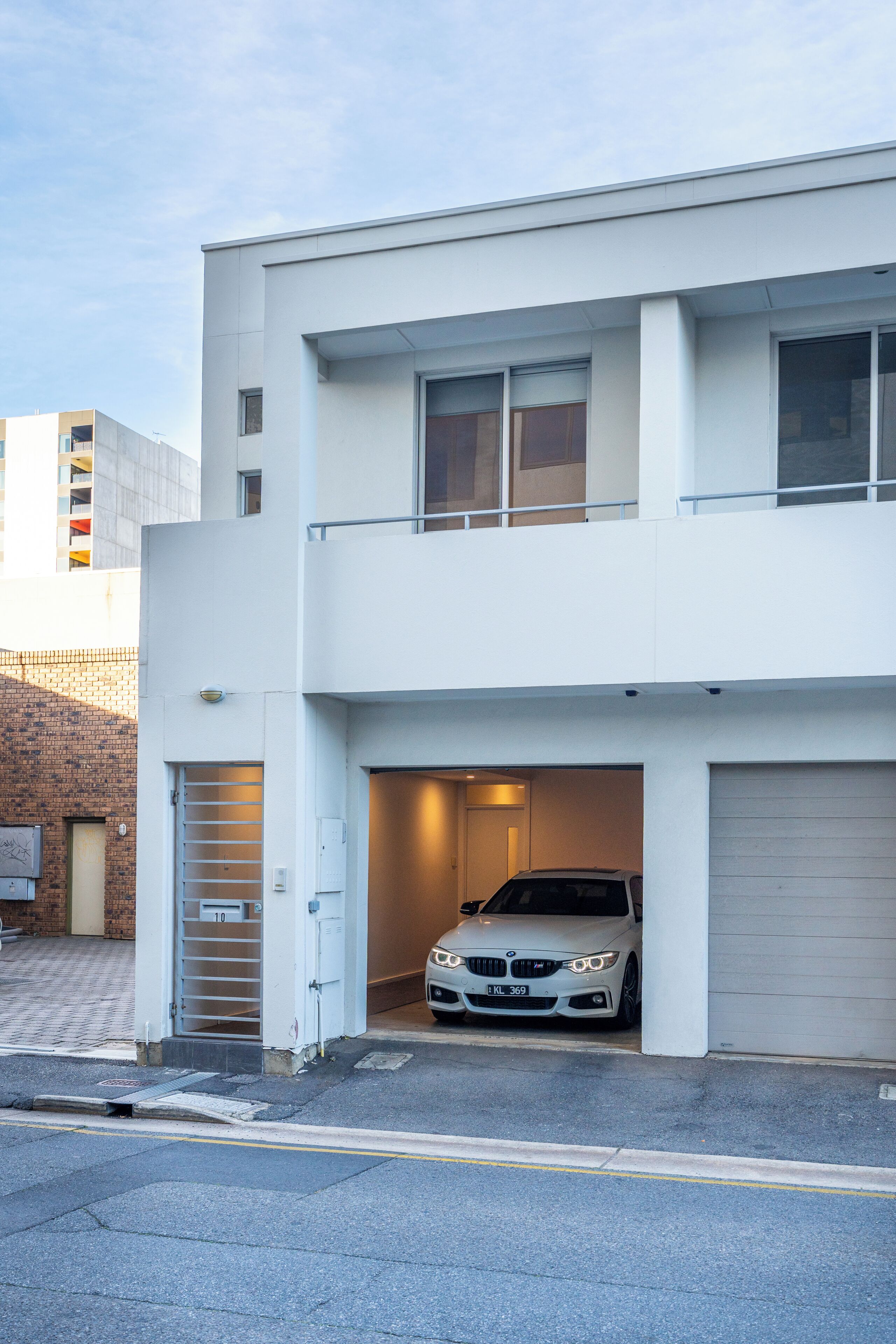 A modern two-story building with a car parked in the garage.