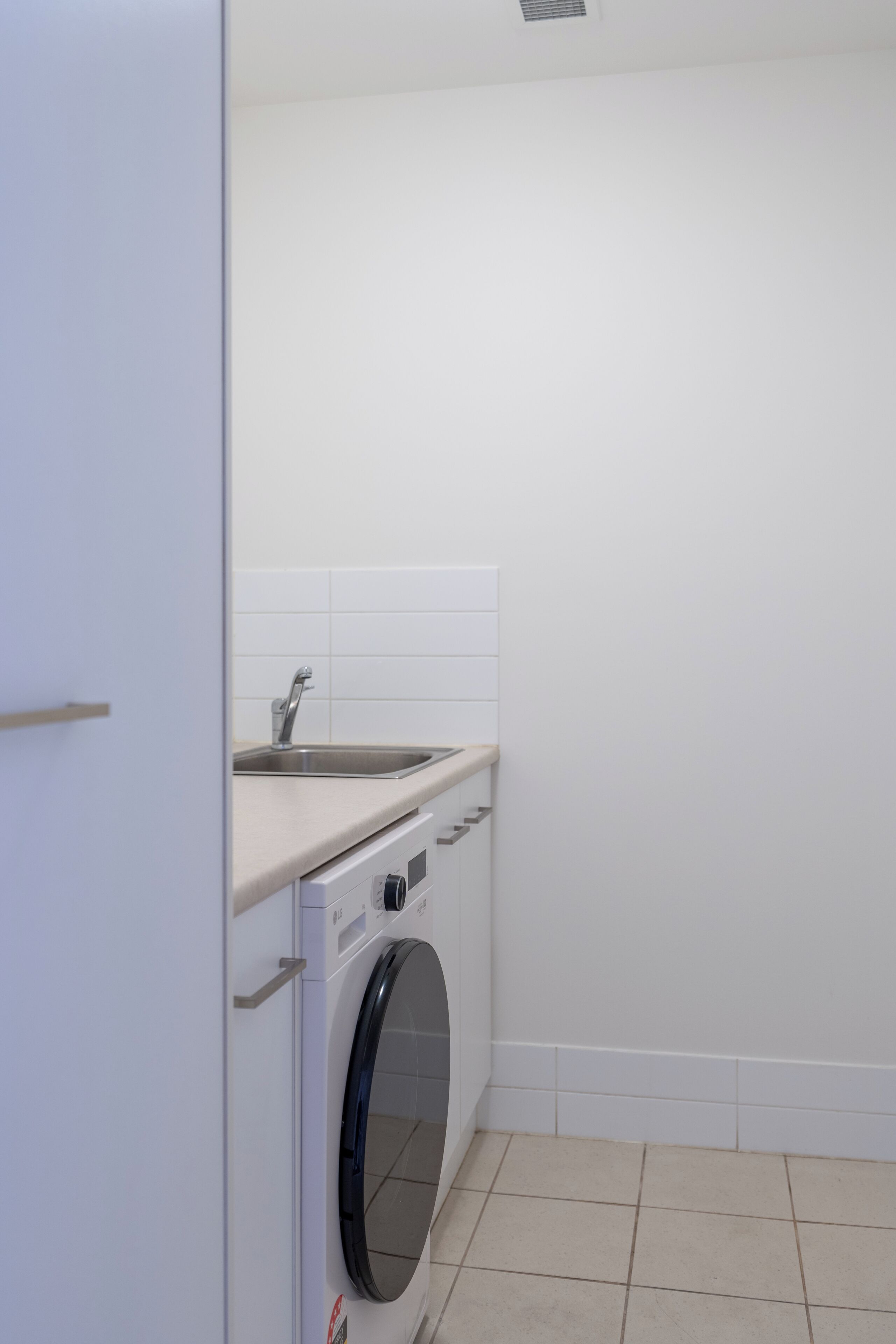 A compact laundry area with a washing machine, a sink, and a small countertop.