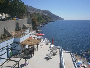 Eine Seeterrasse mit Sitzgelegenheiten im Freien, einem Geländer und Blick auf den Ozean.