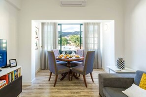 A dining area with a table set for two, a sofa, and a television. - Enjoy the city center at fully equipped 2 BR w/ AC (Funchal)