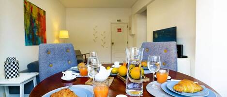 A breakfast table with croissants, orange juice, and water glasses.