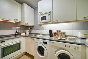 A compact kitchen with a microwave, oven, and washing machine. - Modern apartment with pool and garage (Lisbon)