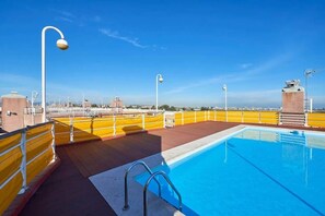 A rooftop pool with a clear view of the city skyline, yellow railings, and a few street lamps. - Modern apartment with pool and garage (Lisbon)