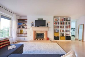 Ein Wohnzimmer mit Kamin, Fernseher und Bücherregalen.