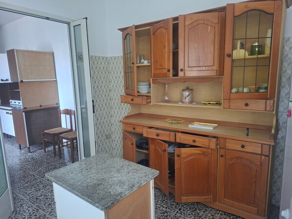 Une cuisine avec des meubles en bois, un plan de travail en granit et une chaise.