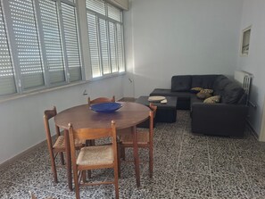 Un salon comprenant une table à manger, des chaises, un canapé noir et un sol à motifs.