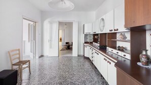 A modern kitchen with white cabinets, a wooden countertop, and a hanging light fixture.
