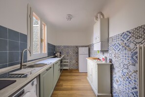 A compact kitchen with a sink, white cabinets, a refrigerator, and patterned tiles. - Cellini's Historic Apartment • Historic Center • 5 min to the Duomo •10 min from the station (Firenze)