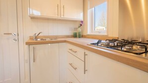 Een keuken met witte kastjes, een houten aanrecht, een gasfornuis en een raam.