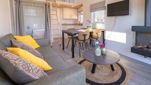 Een modern interieur met een bank, eettafel, stoelen, een televisie en een open haard.