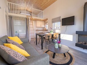 Ein modernes Interieur mit einer Couch, einem Esstisch, Stühlen, einem Fernseher und einem Kamin.