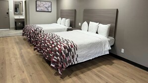 Habitació d'hotel amb dos llits, un bany i un mirall.