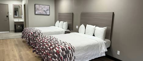 Una habitación de hotel con dos camas, un baño y un espejo.