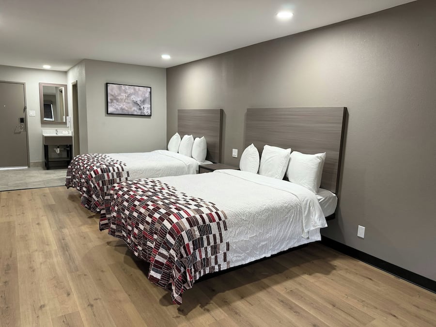 Een hotelkamer met twee bedden, een badkamer en een spiegel.