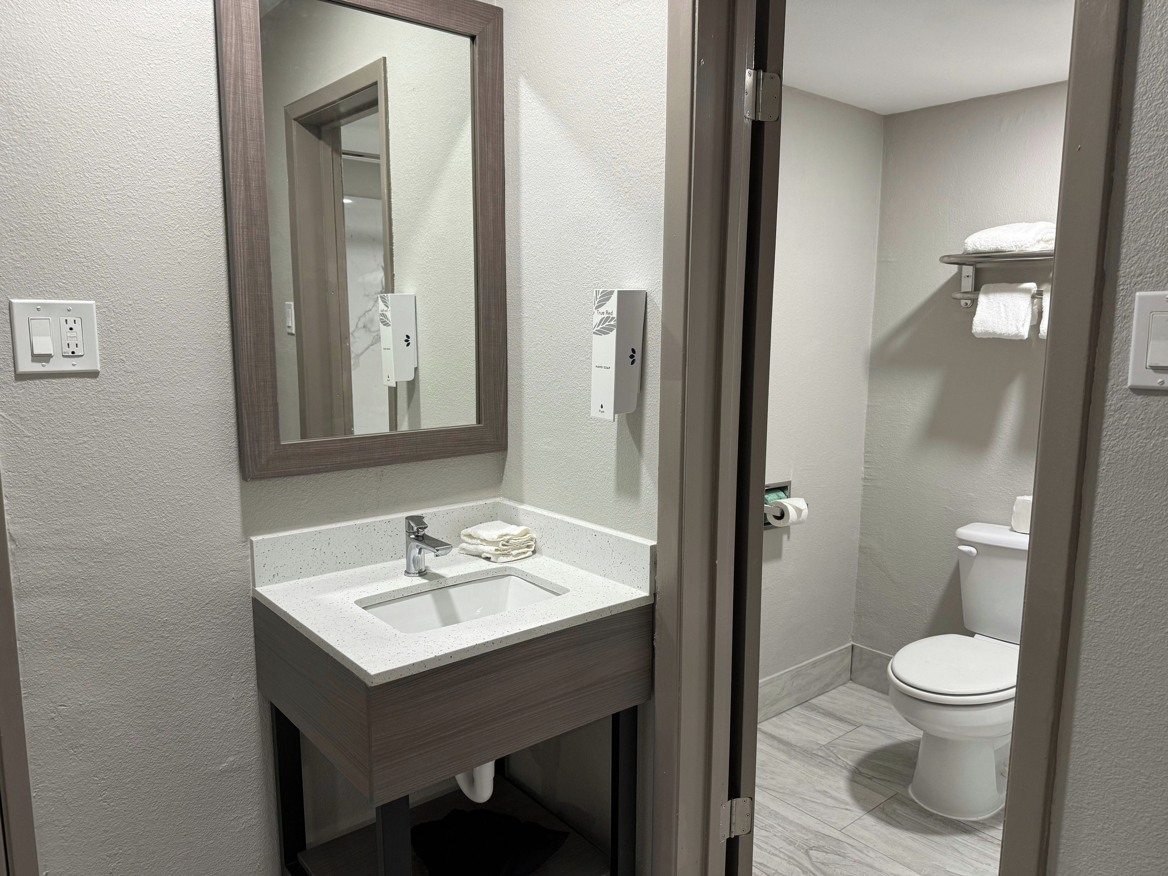A modern bathroom with a white sink, a mirror, and a toilet.