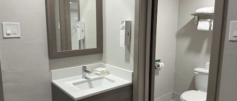 A modern bathroom with a white sink, a mirror, and a toilet.