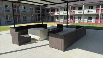 An outdoor patio area with wicker furniture and a covered section.