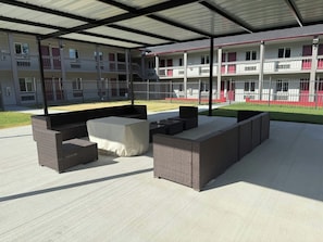 An outdoor patio area with wicker furniture and a covered section. - Red Roof Inn Sherman (Sherman)