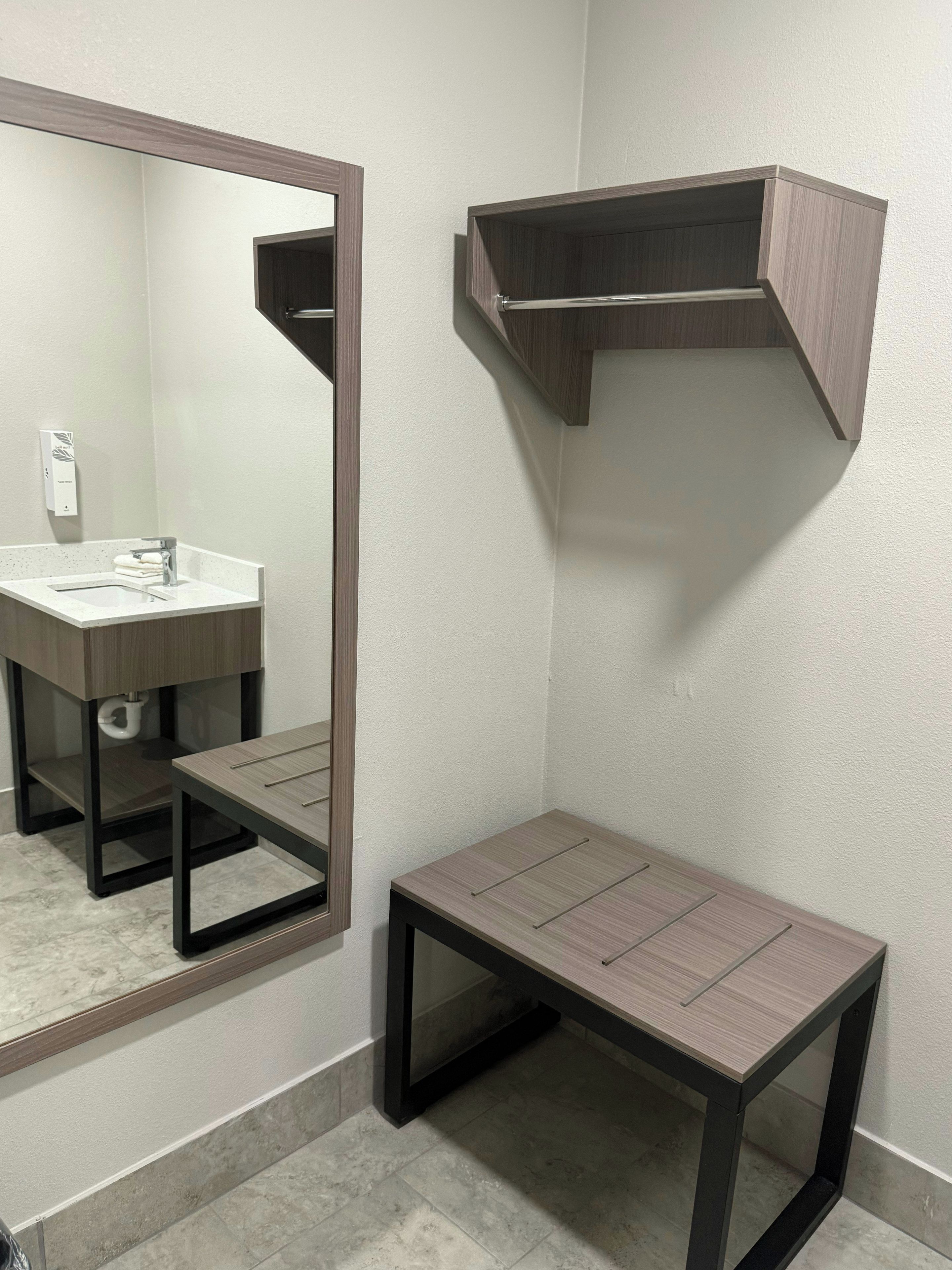 A bathroom with a mirror, sink, and a small table.