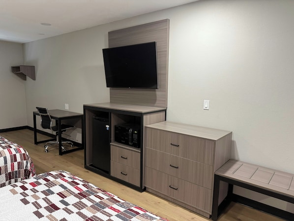 Un dormitorio con una cama, un escritorio con silla, un televisor y un armario.