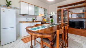 A kitchen with a dining table, chairs, a refrigerator, cabinets, a microwave, and a television. - Apartment 'Casa Melody' with Balcony (Olmedo)