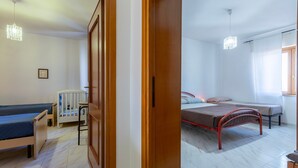 A bedroom with two beds, a wooden wardrobe, a radiator, and a hanging light fixture. - Apartment 'Casa Melody' with Balcony (Olmedo)