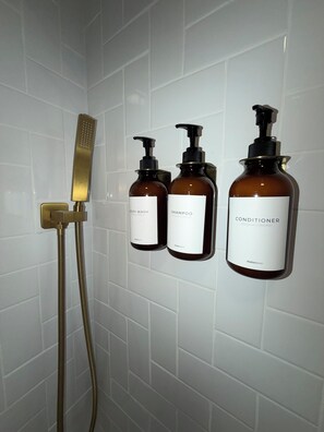 Ein Badezimmer mit Dusche, zwei Shampoo-Flaschen und einer Conditioner-Flasche.