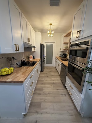 Eine moderne Küche mit weißen Schränken, Edelstahlgeräten und einer Holz Arbeitsplatte.