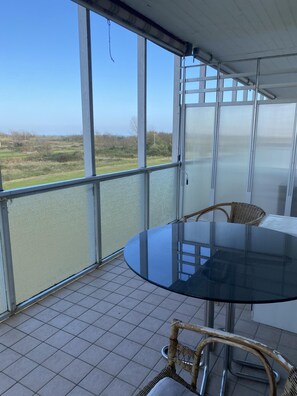 A balcony with a glass table and wicker chairs, overlooking a grassy field. - Ca Festa Residence: Two-room apartment Ca Festa 51 for 6 people (Chioggia)