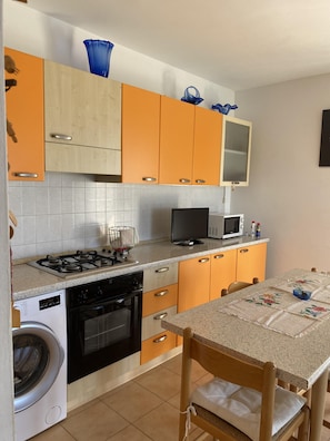 A kitchen with a stove, microwave, oven, and washing machine. - Ca Festa Residence: Two-room apartment Ca Festa 51 for 6 people (Chioggia)