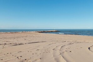 A sandy beach with footprints leading to a rocky breakwater. - Residenz Arcobaleno, Stella Marina 2 Two-Room Apartment for 4 People (Chioggia)