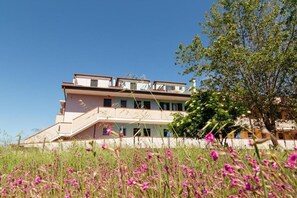 A multi-story building with a balcony, surrounded by a field of pink flowers. - Residenz Arcobaleno, Stella Marina 6 Two-Room Apartment for 4 People (Chioggia)
