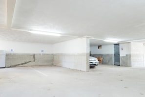A parking garage with concrete walls, numbered parking spots, and a white car parked in one spot. - Residenz Arcobaleno, Stella Marina 6 Two-Room Apartment for 4 People (Chioggia)