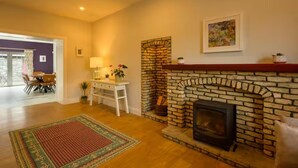 A living room with a fireplace, a dining area with chairs, a table, and a rug. - The Stone House Sleeps 10 With Parking (Clarinbridge)