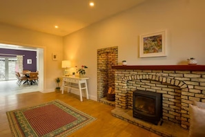 Una sala de estar con chimenea, un comedor con sillas, una mesa y un tapete.