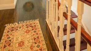 A staircase with a wooden handrail and a patterned rug on the floor. - The Stone House Sleeps 10 With Parking (Clarinbridge)