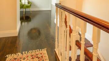 A staircase with a wooden handrail and a patterned rug on the floor.