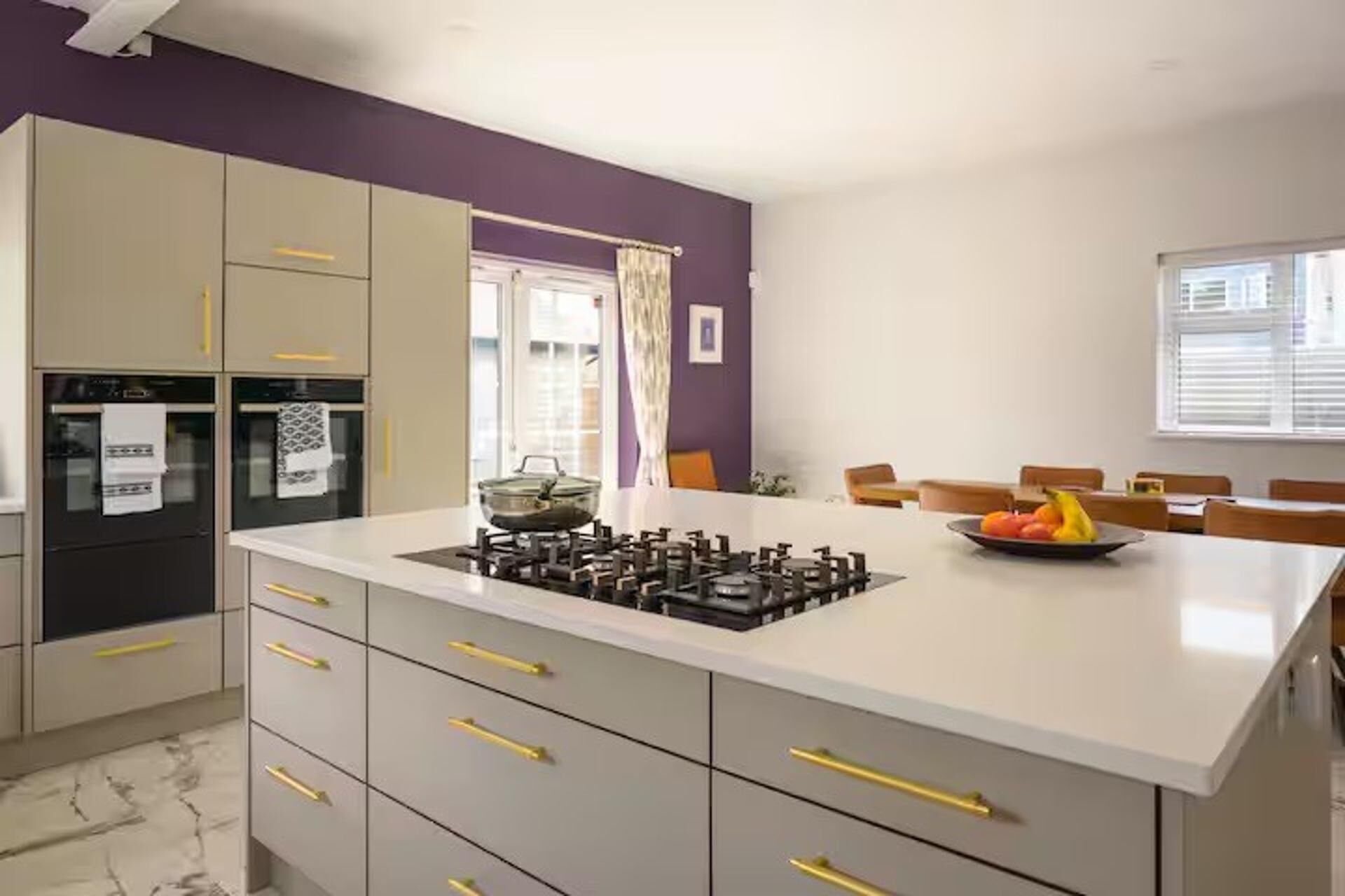 Una cocina moderna con una isla central, electrodomésticos integrados y un comedor con sillas.